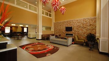 A spacious lobby with a high ceiling, a fireplace, and a seating area with sofas and chairs.