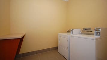 A laundry room with a washing machine and dryer, a countertop, and a tiled floor.