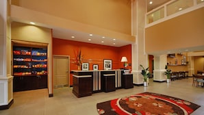 A hotel lobby with a reception desk, a snack bar, and a dining area.