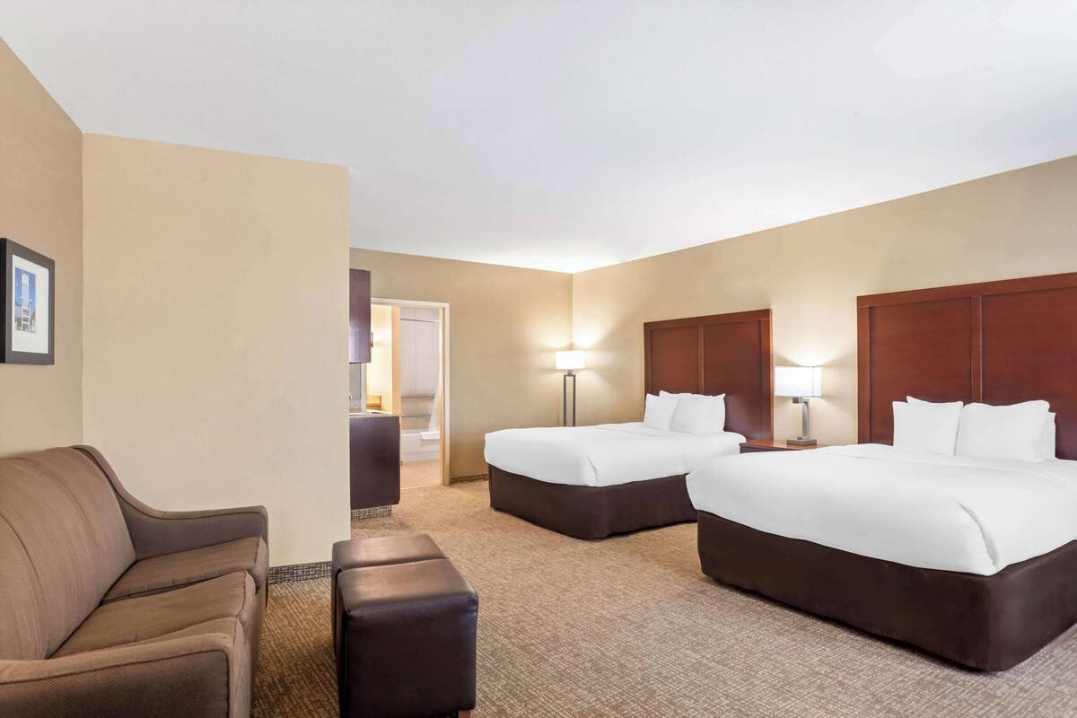 Ein Hotelzimmer mit zwei Betten, einem Sofa, einem Sessel und einem kleinen Tisch.