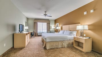 Habitación de hotel con cama, escritorio, silla, televisor y ventilador de techo.