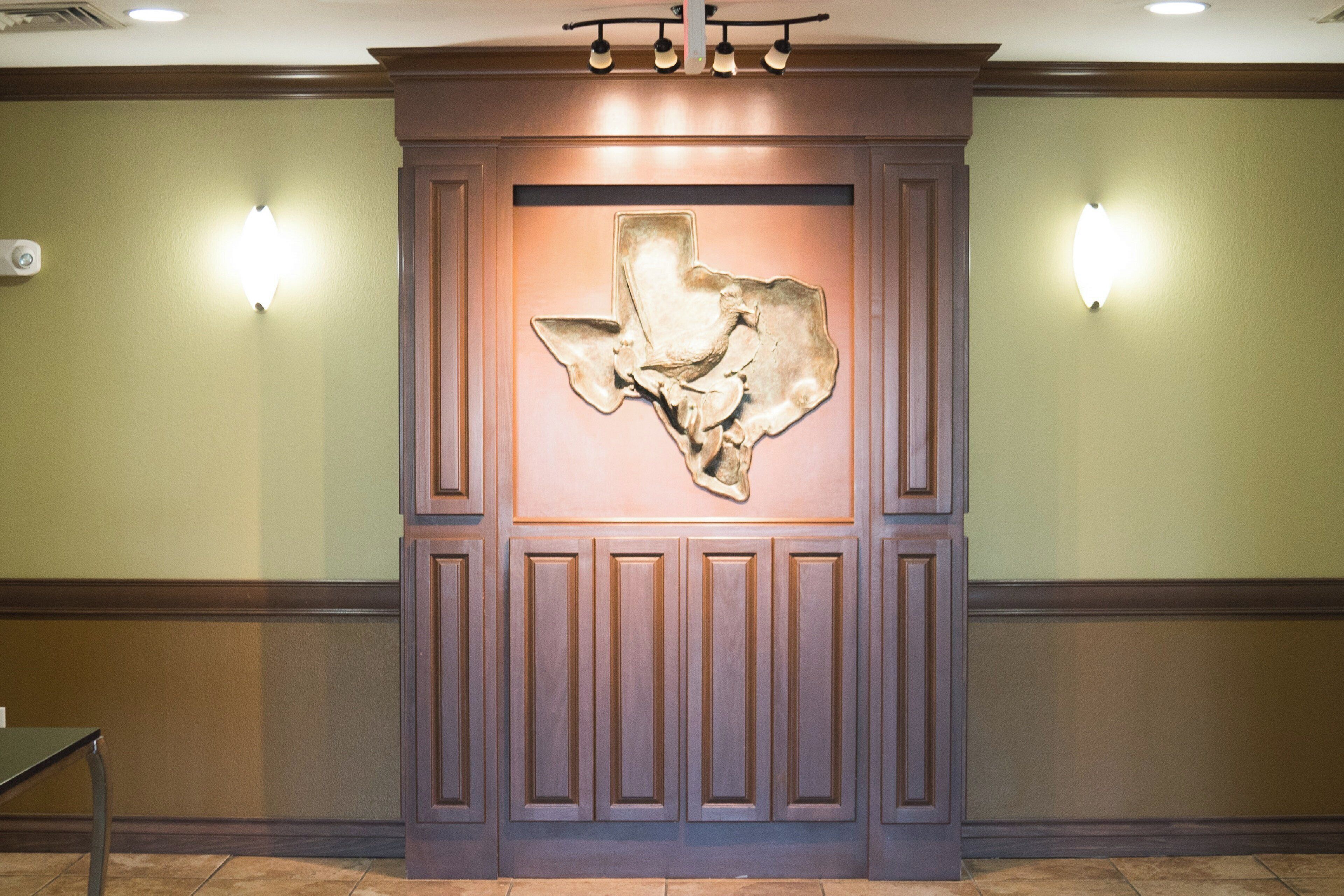 A wall with a decorative panel and two wall-mounted lights.