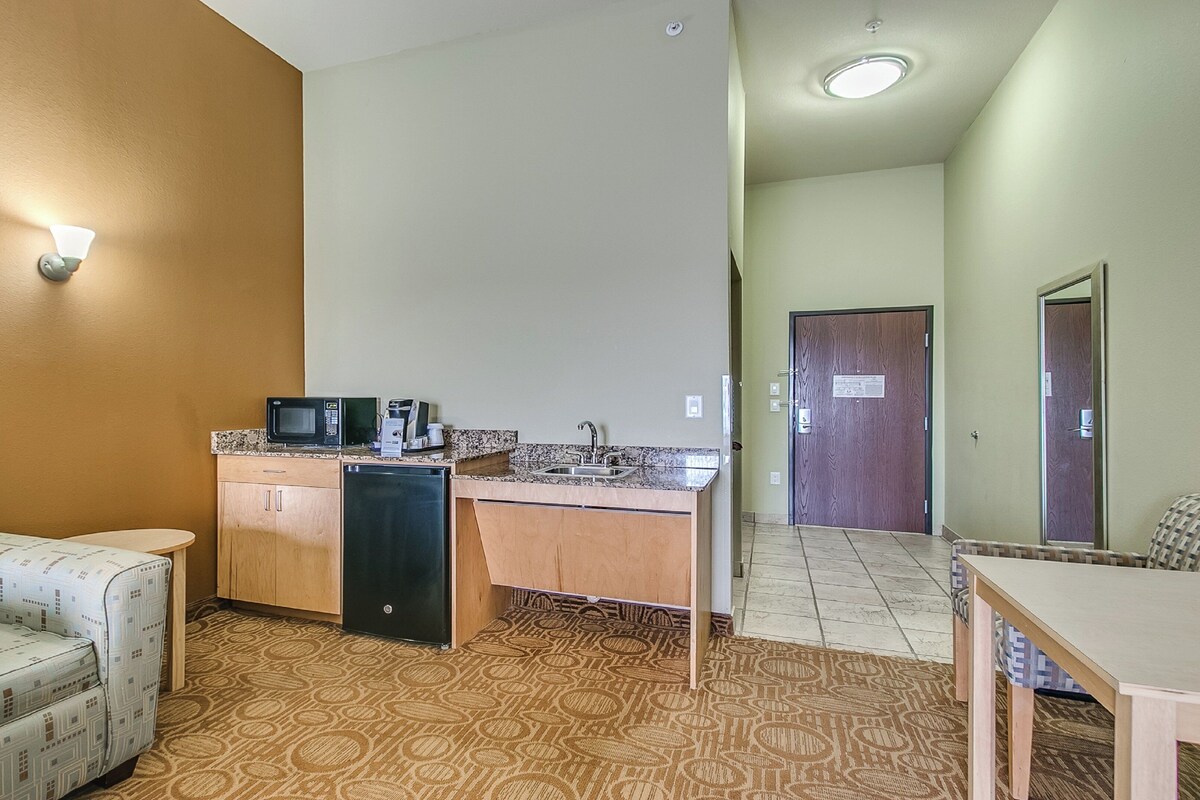 A compact living space with a kitchenette, a sofa, a dining table, and a patterned carpet.
