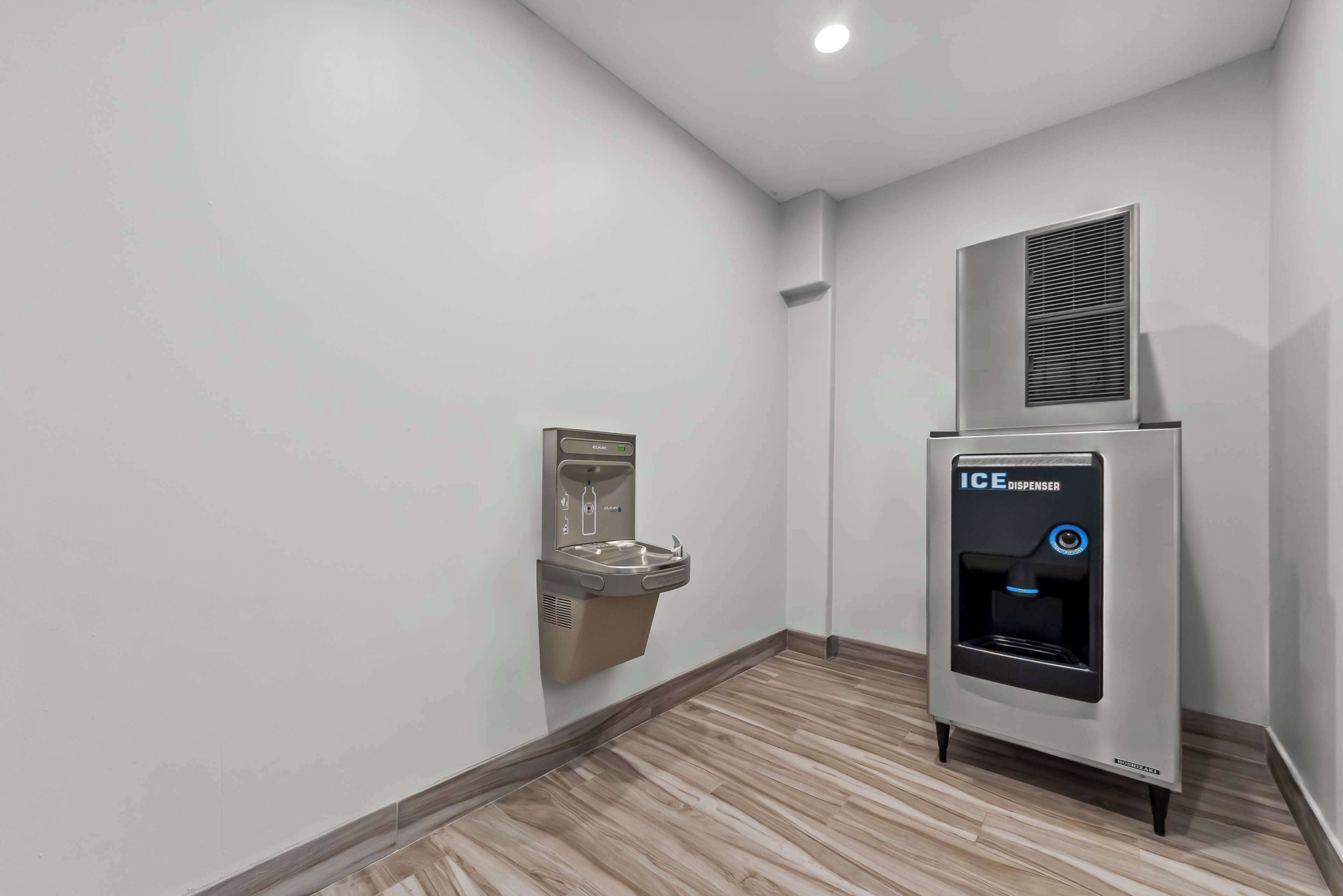 Un baño con un secamanos fijado a la pared y un dispensador de hielo.