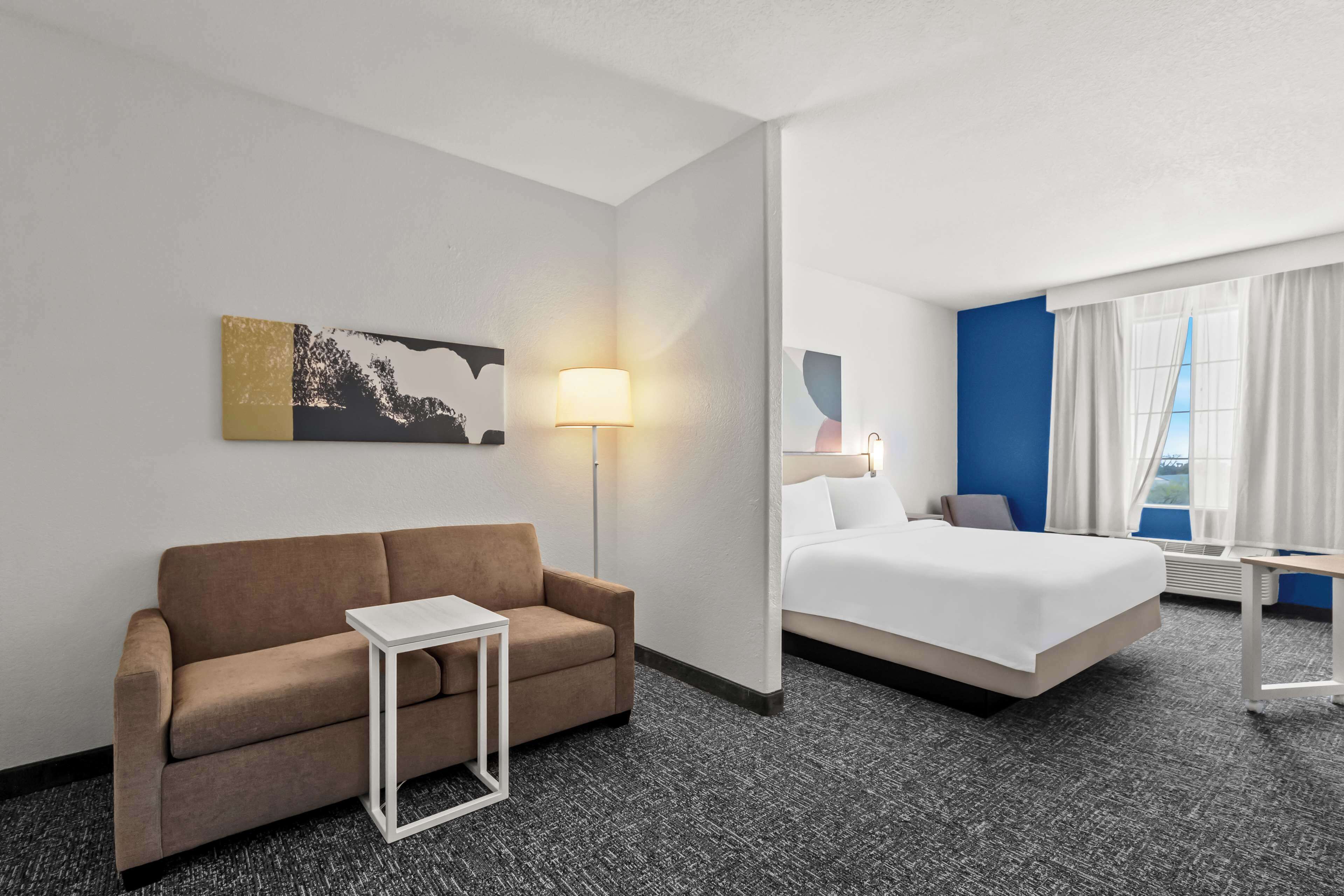 Habitació d'hotel amb un sofà, un llit, una làmpada i un quadre a la paret.
