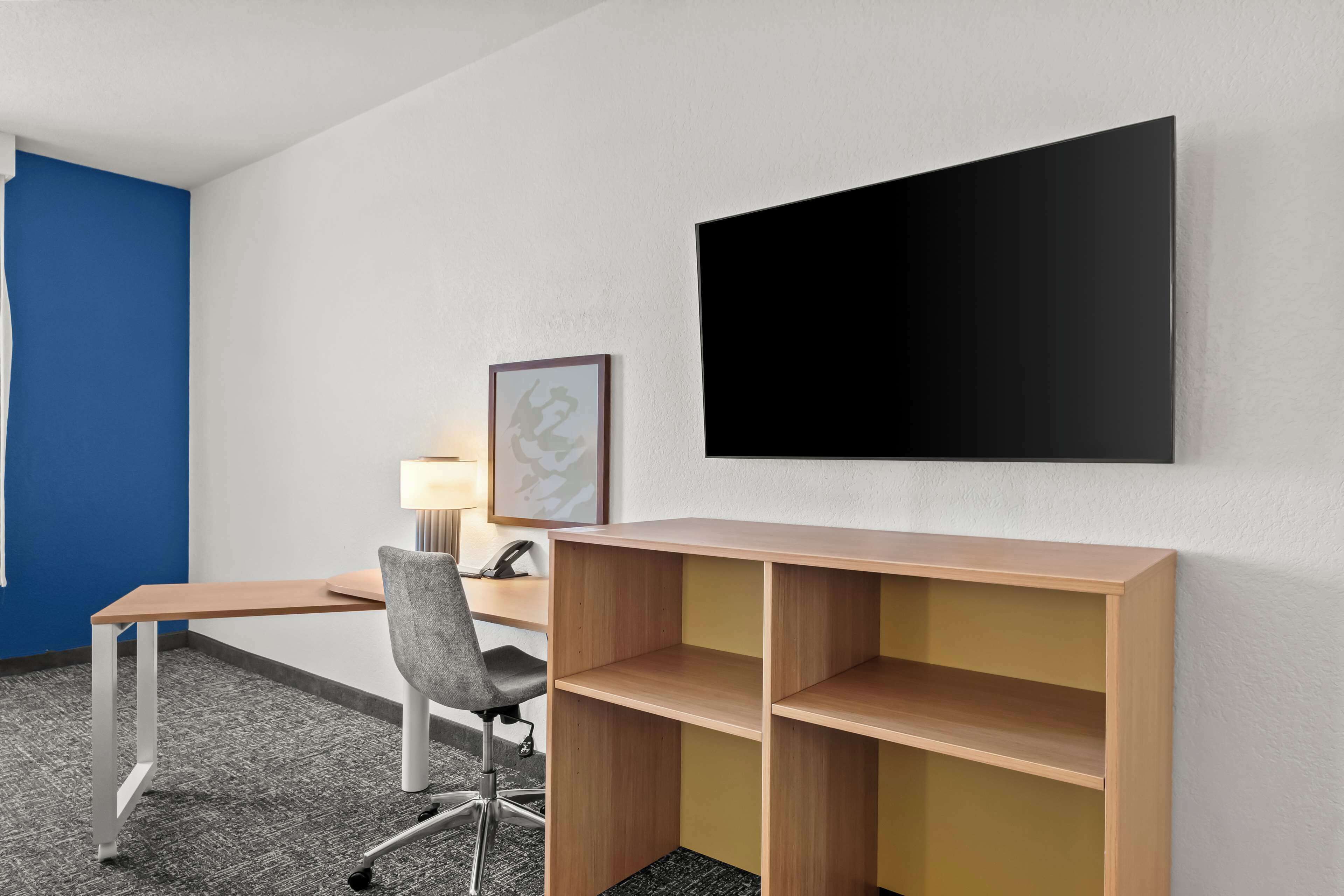 Ett modernt kontorsutrymme med ett skrivbord, en stol och en väggmonterad platt-TV.