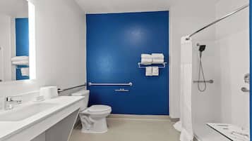 Een moderne badkamer met een blauwe accentmuur, een wit wastafelmeubel, een toilet en een douchegedeelte.