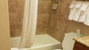 A bathroom with a bathtub, toilet, and a towel rack with towels.