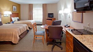 A hotel room with two beds, a desk with a chair, a television, and a microwave.