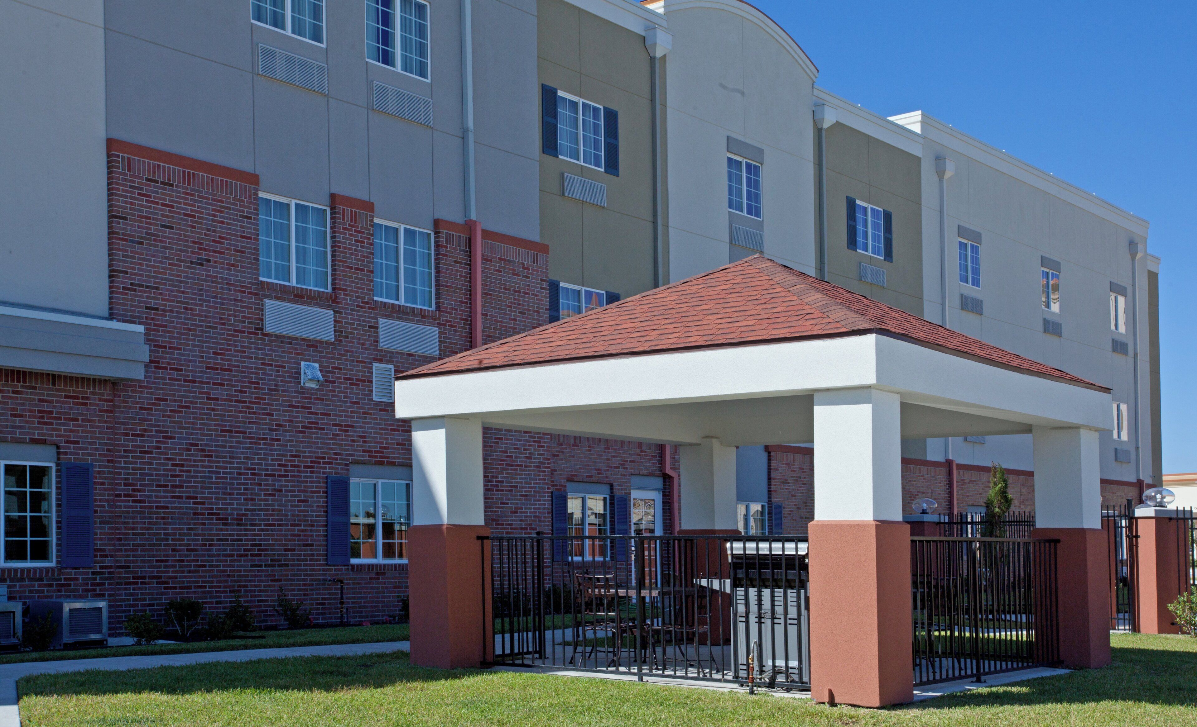 A multi-story building with a covered outdoor seating area, brick walls, and a flat roof.