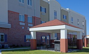 A multi-story building with a covered outdoor seating area, brick walls, and a flat roof.