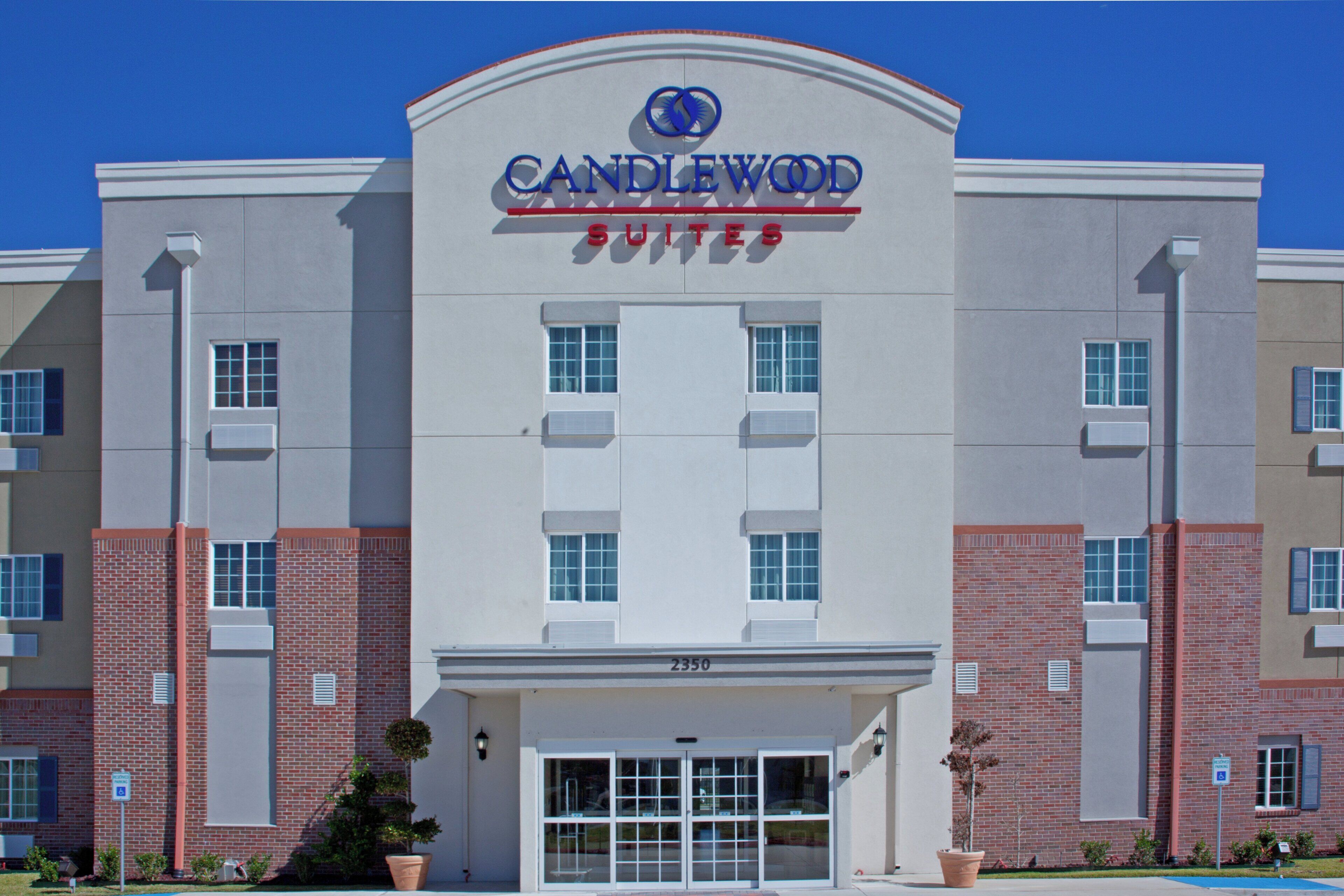 Un hotel con un llamativo letrero 'CANDLEWOOD', múltiples ventanas y fachada de ladrillo.
