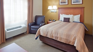 Een hotelkamer met een groot bed, een stoel, een bureau en een raam met gordijnen.