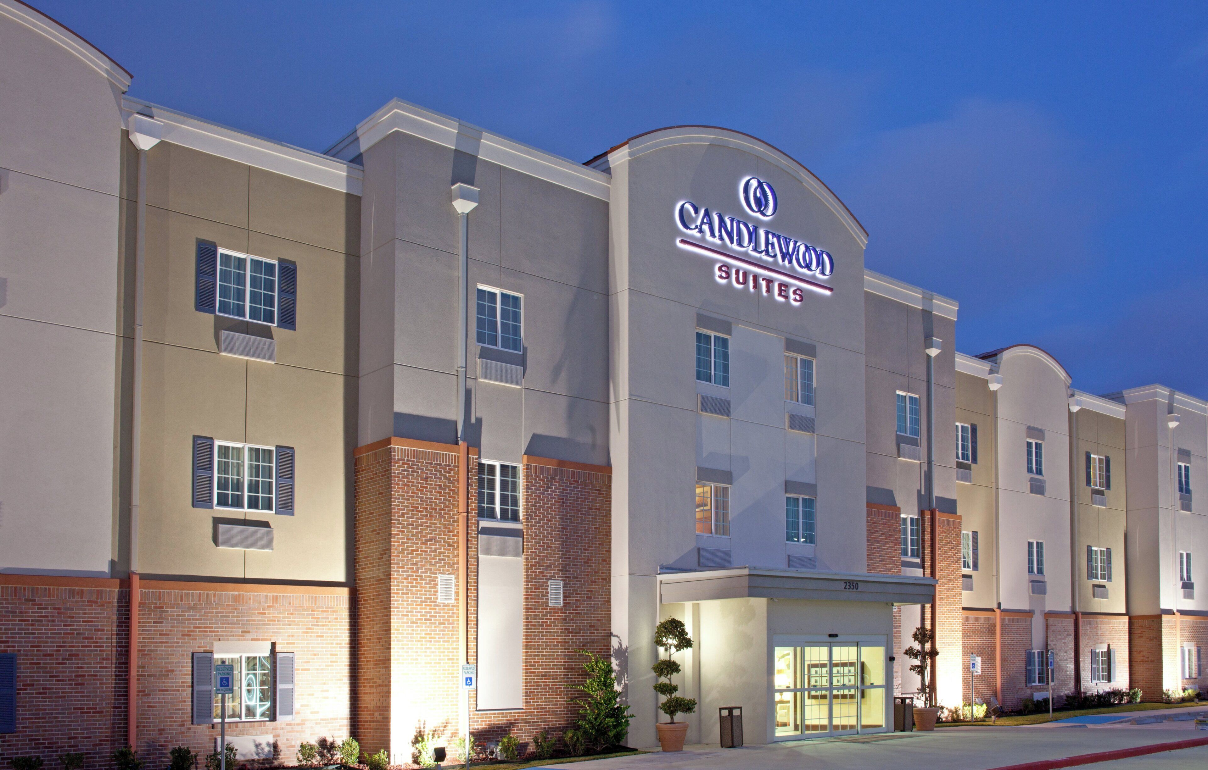 Un hotel con fachada moderna, múltiples ventanales y señalización destacada de 'Candlewood Suites'.