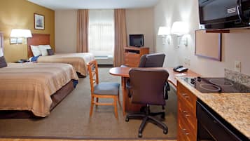 Ein Hotelzimmer mit zwei Betten, einem Schreibtisch mit Stuhl, einem Fernseher und einer Mikrowelle.