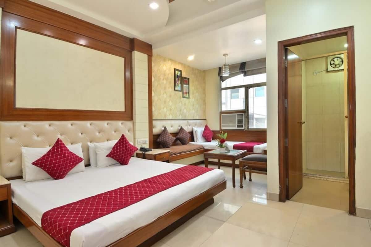 A hotel room with a large bed, a sofa, a desk, and a door.
