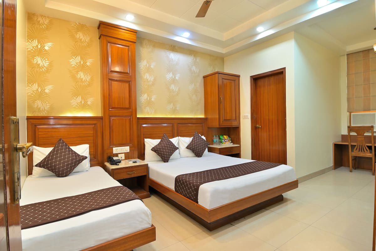 A hotel room with two beds, wooden headboards, a desk, and a chair.