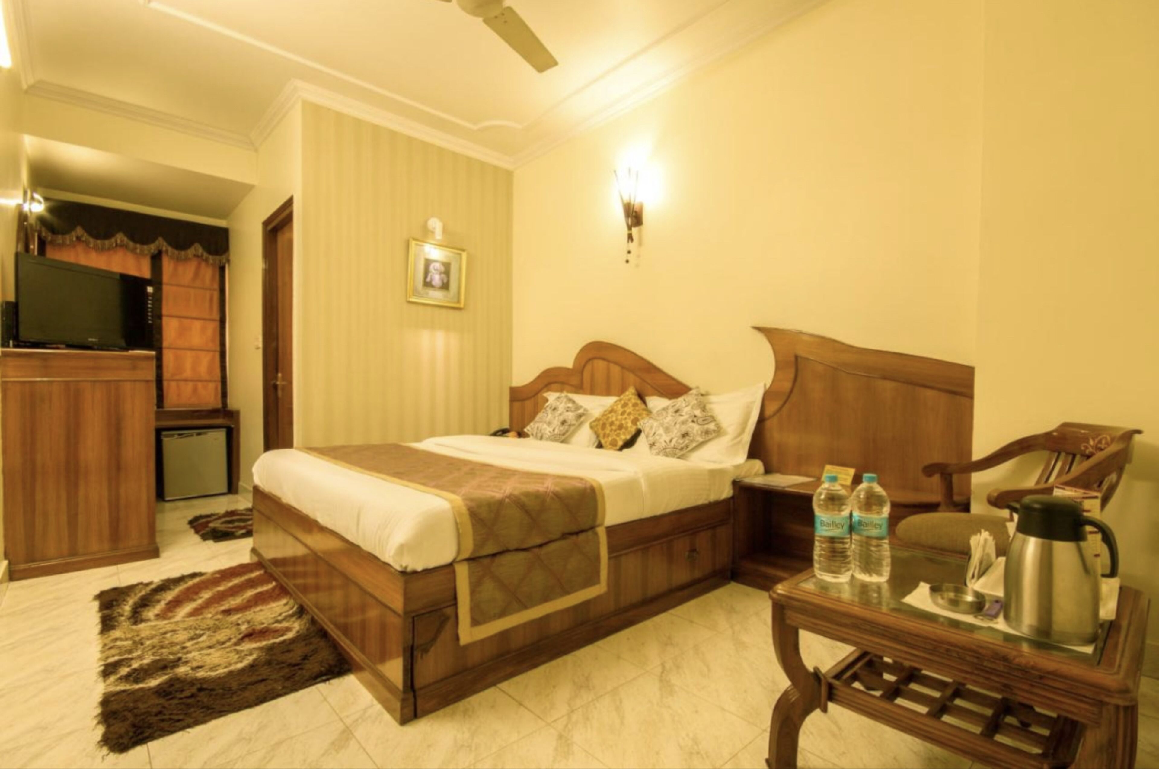 Quarto bem arrumado com cama de madeira, mesas de cabeceira, televisão e máquina de café.