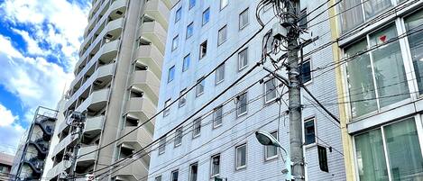 A multi-story building with a cafe and restaurant on the ground floor, a tall adjacent building, and a street with a traffic light.