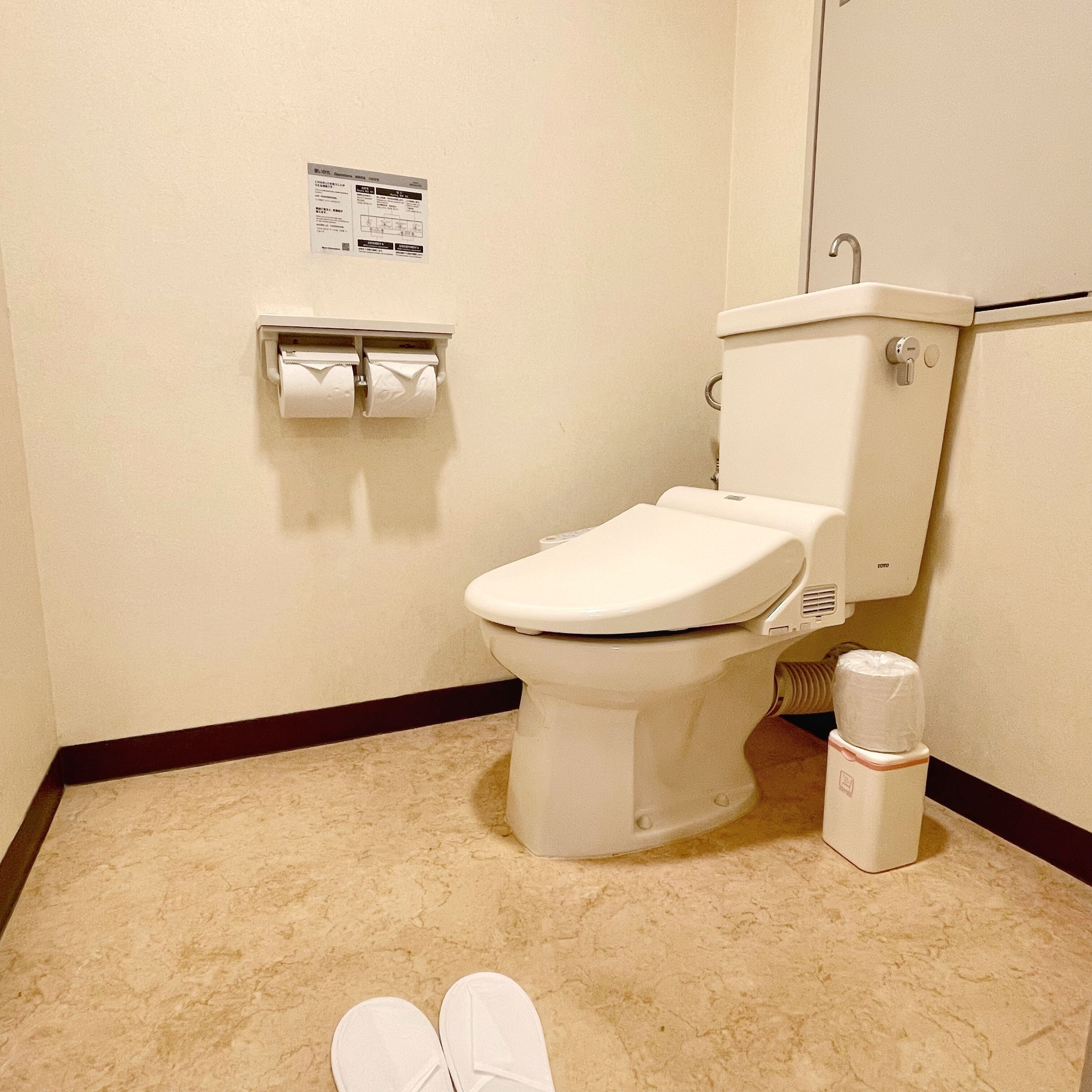 Un baño pequeño y limpio con inodoro, dispensador de toallas de papel y soporte para papel higiénico.