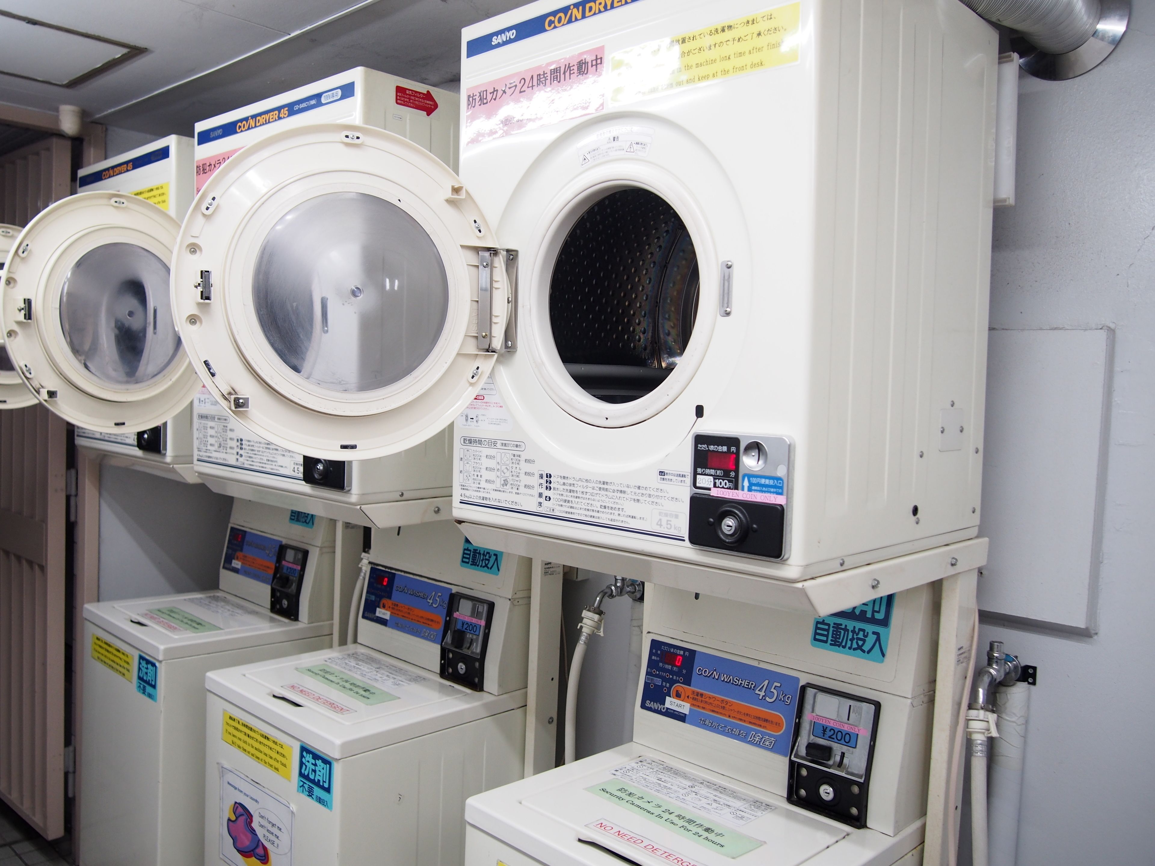 Een rij witte wasmachines met voorlader en bedieningspanelen, elk voorzien van Japanse tekst.