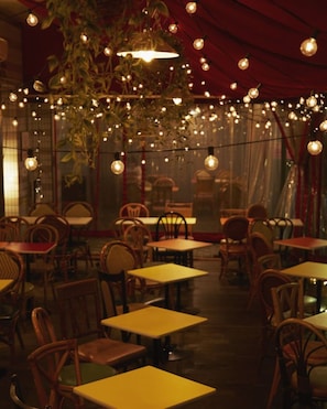 An indoor dining area with tables and chairs, string lights, and hanging plants. - Sakura Hotel Ikebukuro - Hostel (Tokyo)