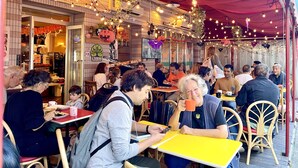 A bustling outdoor cafe with tables and chairs, a red awning, and hanging lights. - Sakura Hotel Ikebukuro - Hostel (Tokyo)