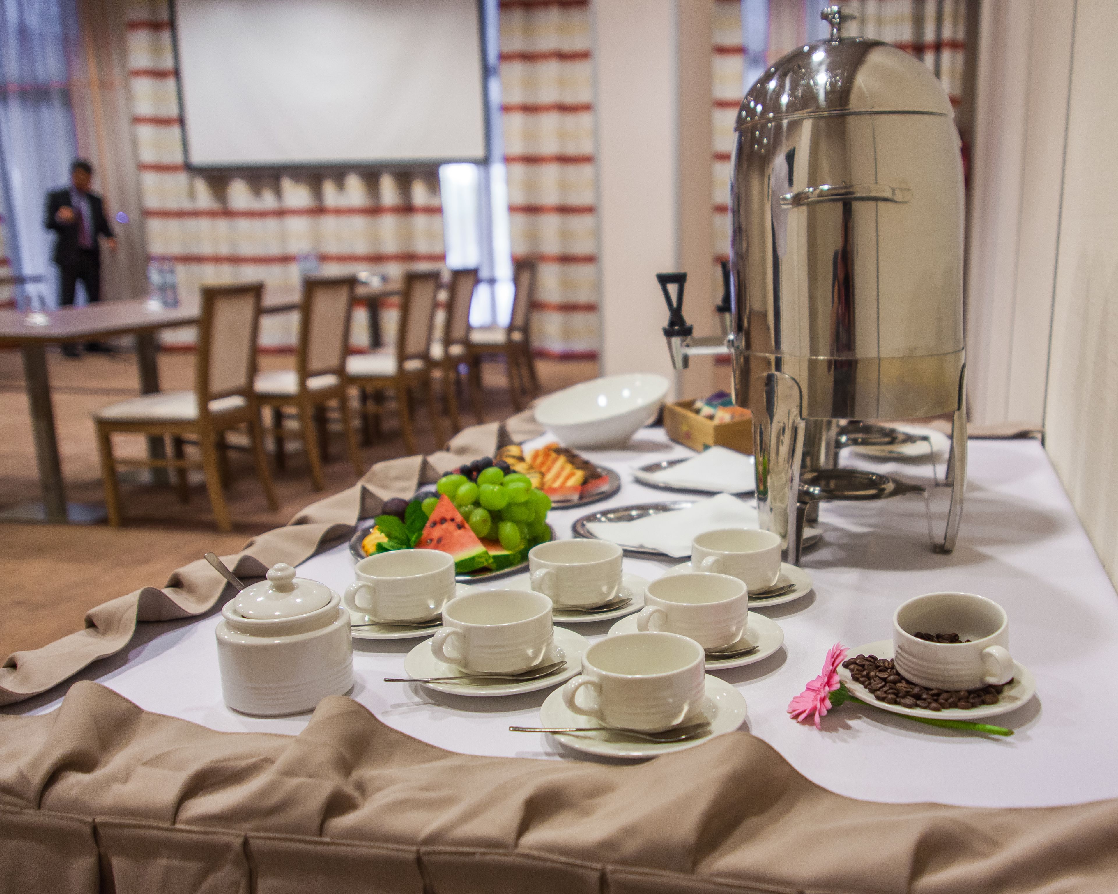 A buffet table with white dishes, a coffee pot, and a fruit platter.