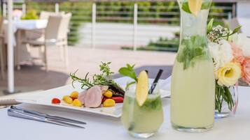 Een gedekte tafel met een bord eten, een hoog glas groen drankje en een kleiner glas met een citroen.