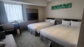 A hotel room with two beds, a desk, a chair, a TV, and a painting on the wall.