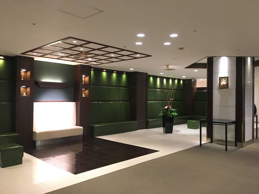 A modern lobby with a reception desk, seating area, and a large potted plant.