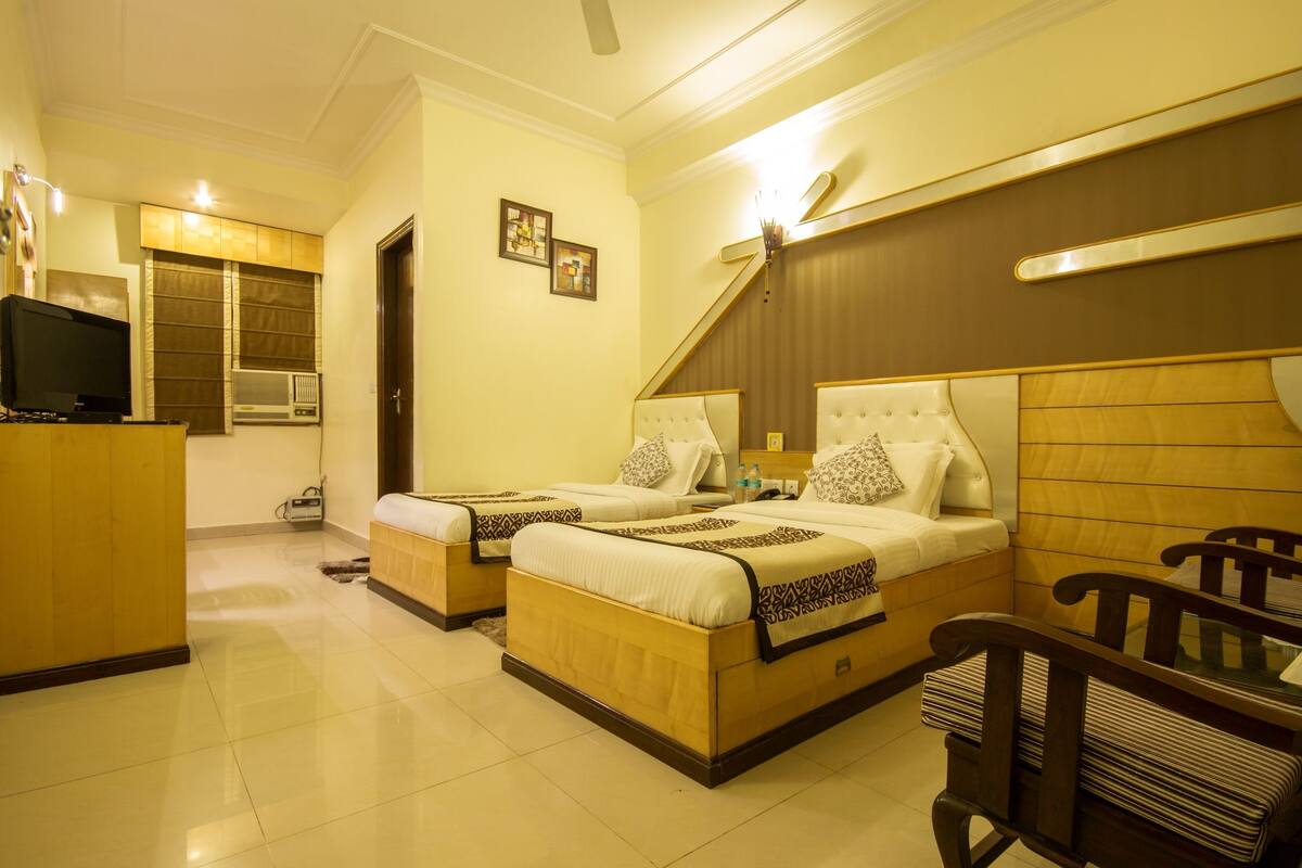 A hotel room with two beds, a TV, a desk, and a chair.