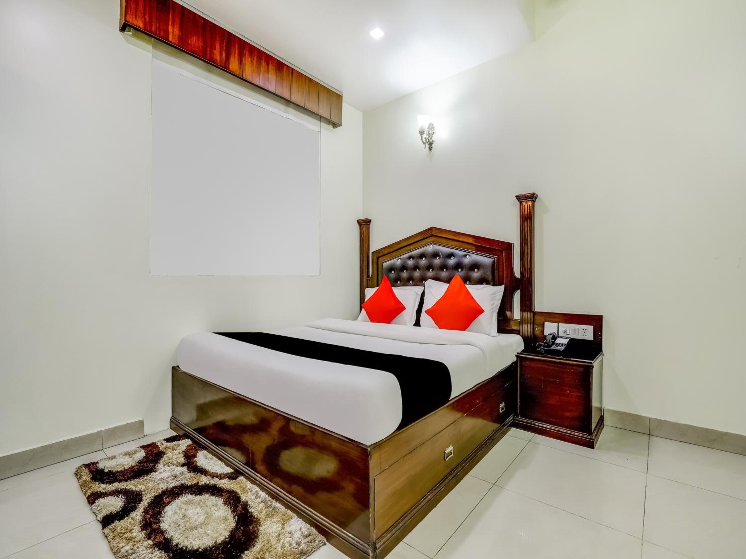 A neatly arranged bedroom with a wooden bed, a bedside table, and a wall-mounted light fixture.