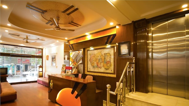 A reception area with a wooden reception desk, a staircase, and a view of the street outside. - Hotel Grand Park Inn (New Delhi)