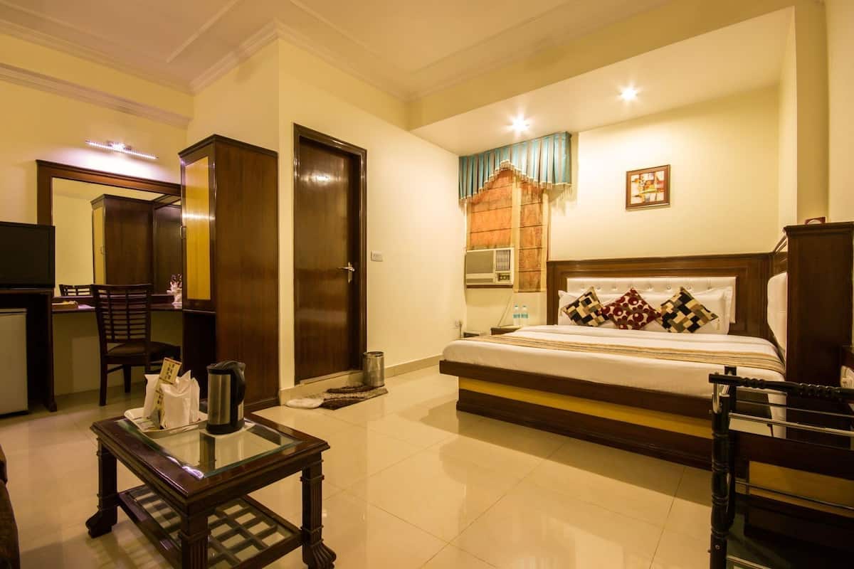 A hotel room with a bed, a desk, a chair, a television, a mirror, and a window with curtains.