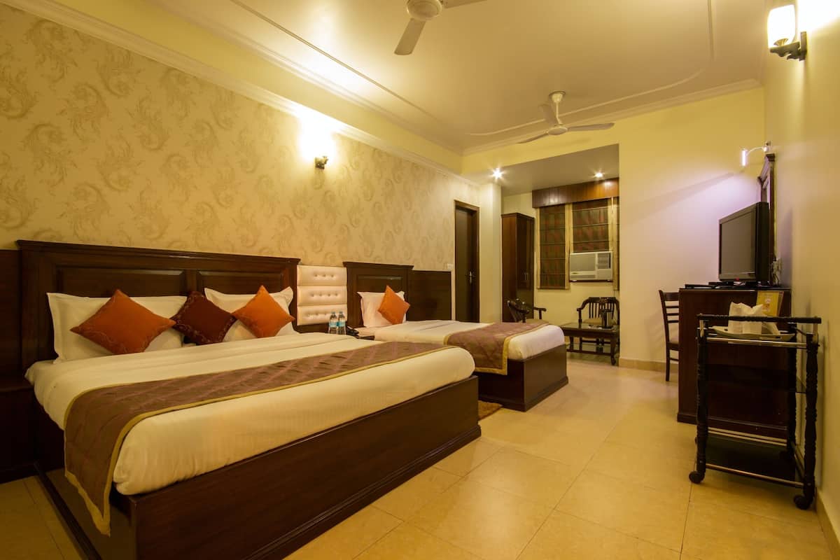 A hotel room with two beds, a desk, a chair, a television, and a ceiling fan.
