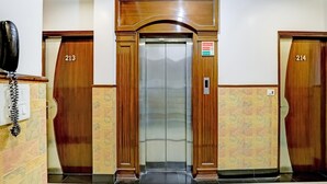 An elevator with a wooden frame and a glass door, flanked by two doors labeled 213 and 214. - Hotel Grand Park Inn (New Delhi)