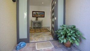 Una puerta que da a un cuarto con una mesa de comedor y sillas, un cuadro en la pared y una planta en maceta.
