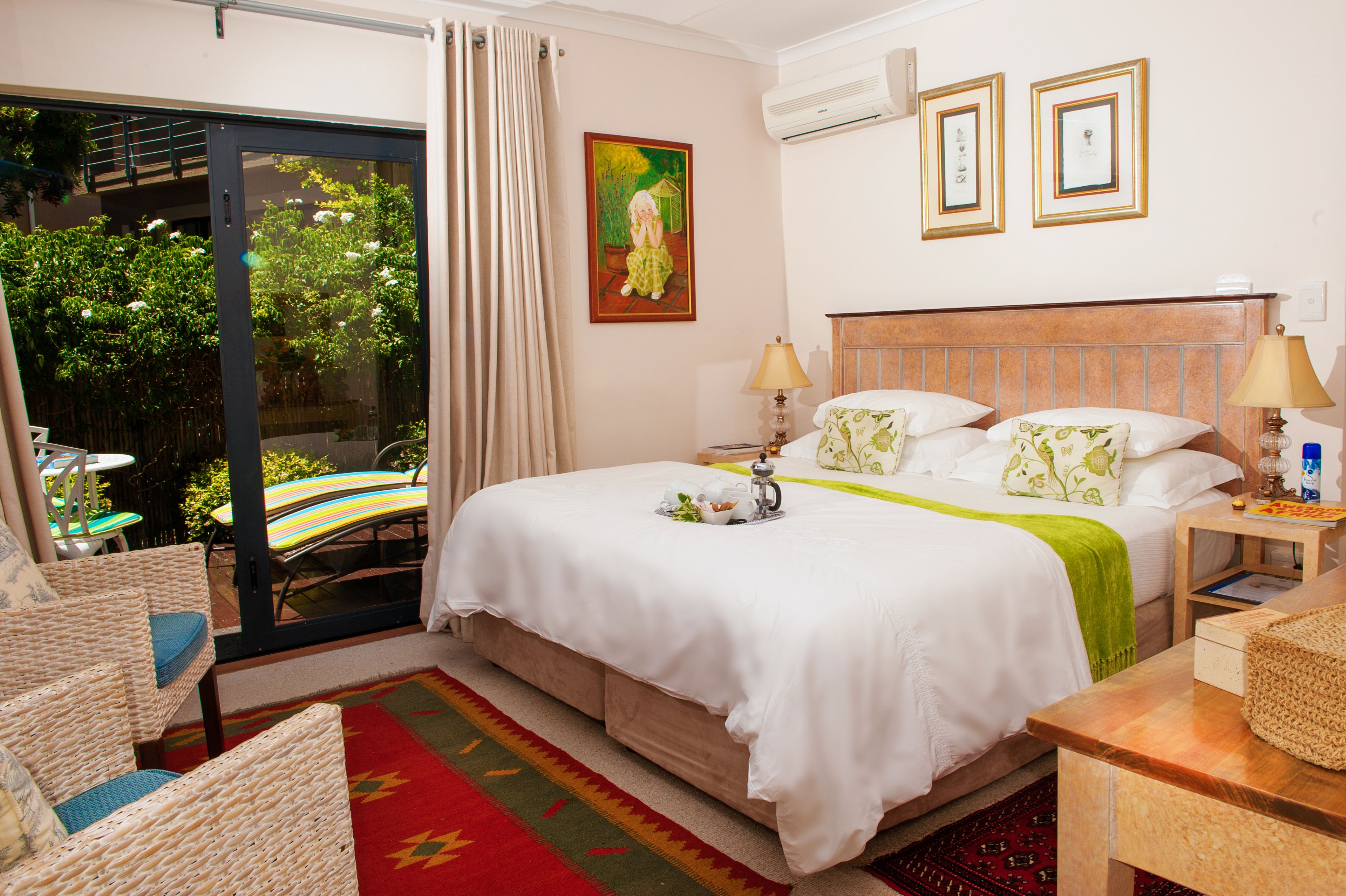 A hotel room with a bed, two bedside tables, a chair, a window with curtains, and a painting on the wall.
