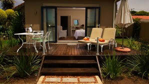 Un hotel con terraza de madera, mobiliario exterior y vistas al interior.