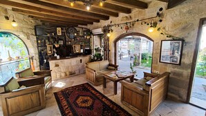 A rustic interior with stone walls, wooden furniture, and a large clock. - Dervish Cave House (Nevsehir)