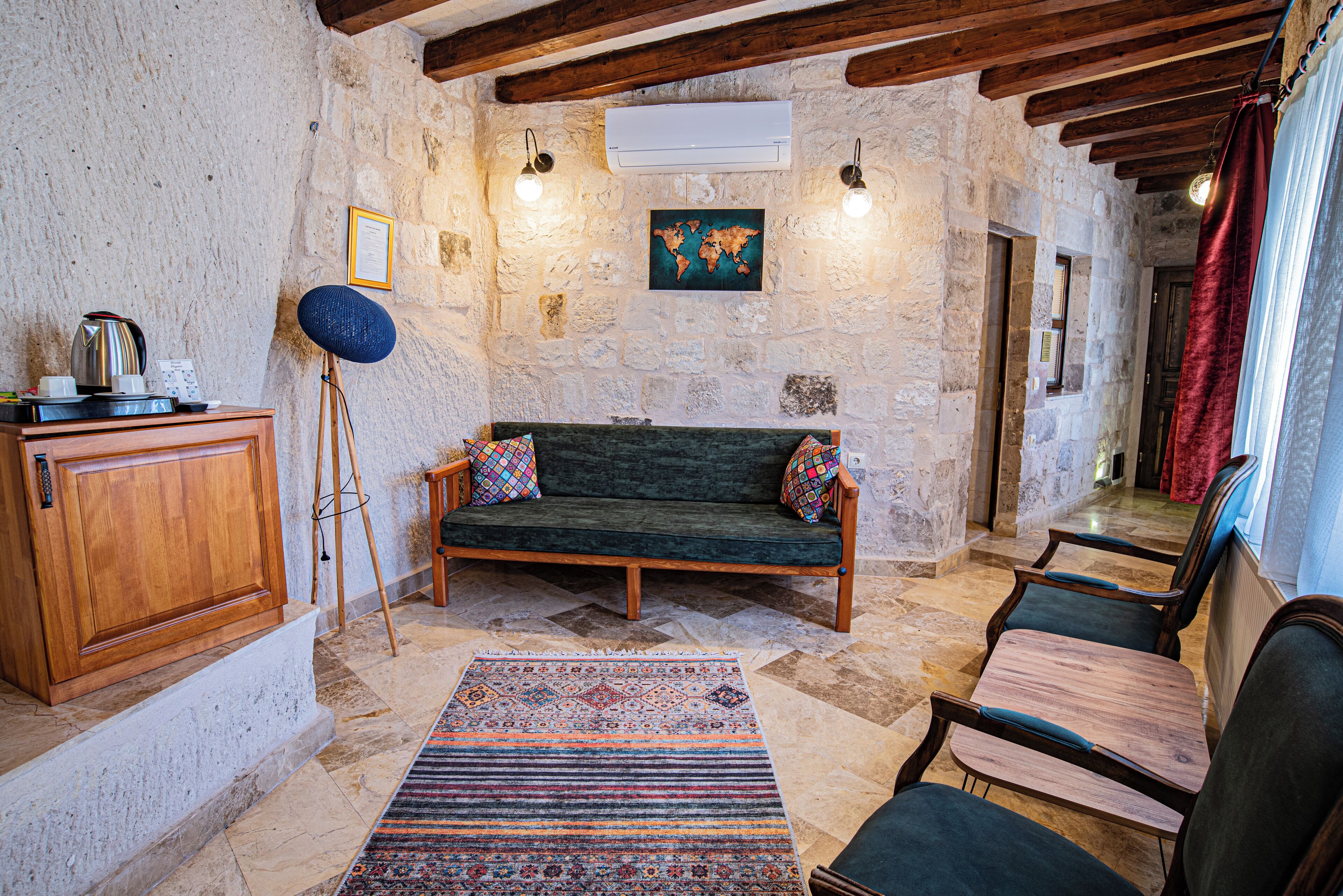 A cozy room with a wooden cabinet, a green sofa, a patterned rug, and a world map on the wall.