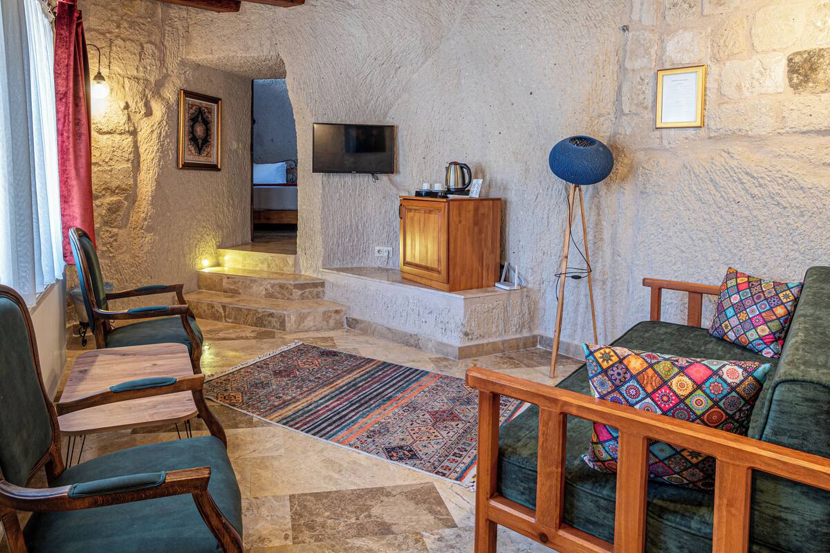 Ein gemütliches Wohnzimmer mit Steinwänden, einem Holzschrank, einem Fernseher und einem farbenfrohen Teppich.