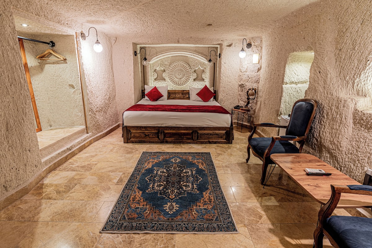 Ein Schlafzimmer mit einem großen Bett, einem Holznachttisch, einem Stuhl, einem Tisch und einer Hängeleuchte.