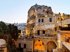 Un edificio histórico de piedra con múltiples balcones y arcos, que destaca por su exterior robusto y una vista del paisaje circundante.