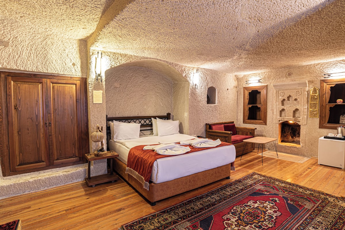 Ein Schlafzimmer mit einem großen Bett, einem Holzschrank und einer Steinwand.