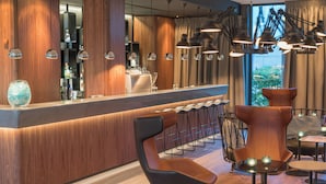 Een moderne barruimte met houten details, barstoelen en hanglampen.