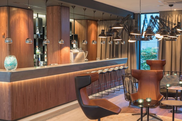 A modern bar area with wooden accents, bar stools, and pendant lighting.