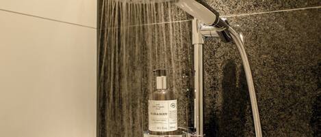 Una ducha con cabezal de ducha de mano y un atomizador de aroma para cabello y cuerpo.