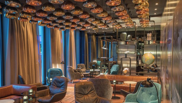 Een moderne lounge met leren banken, glazen tafels en een wereldbol op een plank.